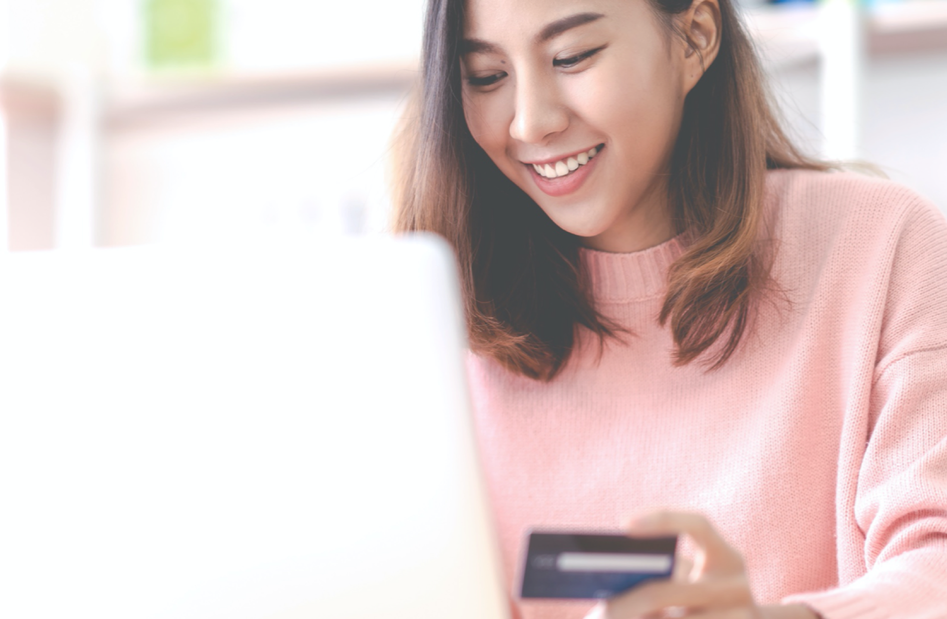 Woman sitting at laptop with credit card in hand.